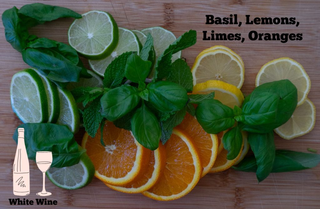 limes, lemons, oranges, basil and mint on a wood cutting board 