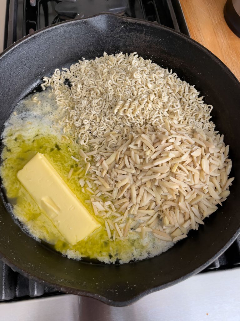 toasting ramen noodles and almonds in frying pan with buttter