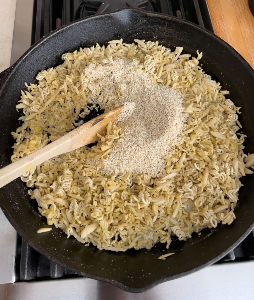 ramen noodles, almonds, and sesame seeds toasting in frying pan