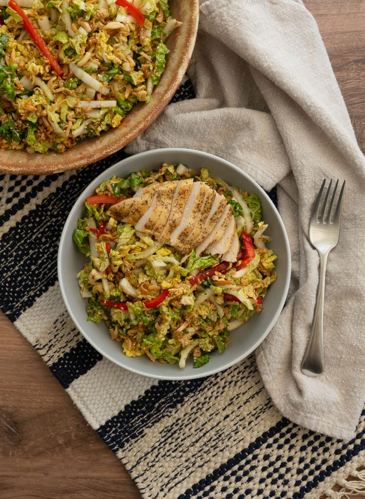 napa cabbage salad topped with a sliced chicken breast