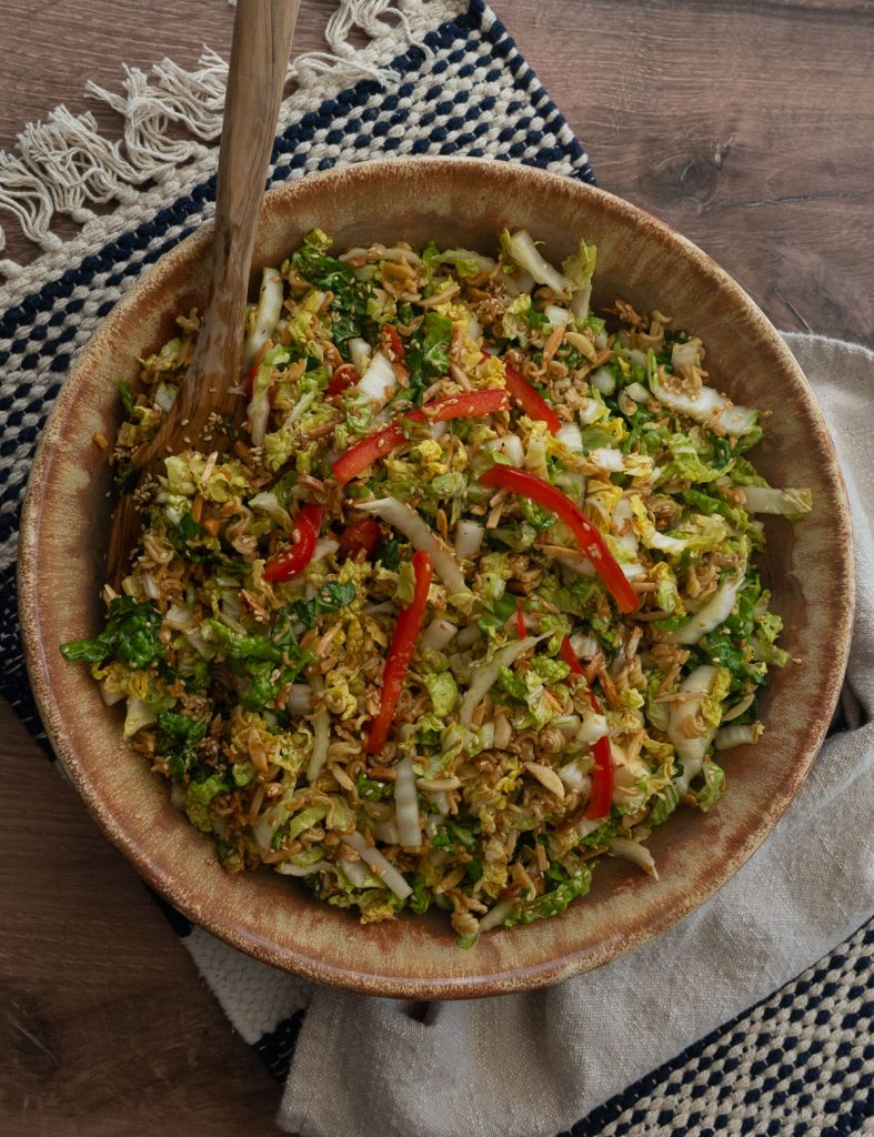 napa cabbage salad in a brown salad bowl with wood serving spoons