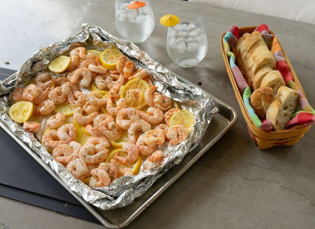 beach shrimp on table with a basket of bread and waters
