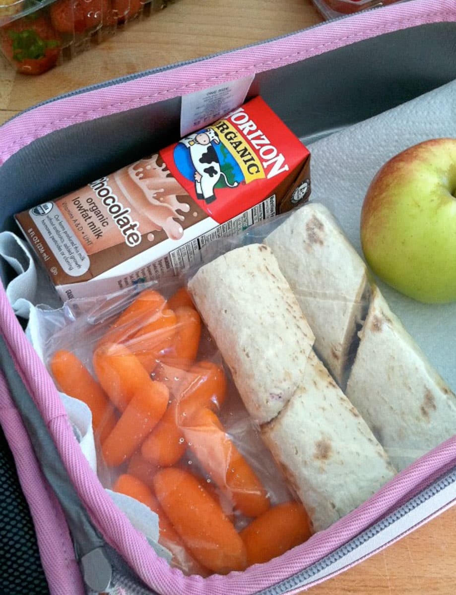 photo of a lunch box with milk, carrots, and wrap sandchich also and apple