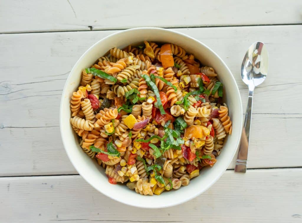 bowl of pasta salad on a white wood picnic table