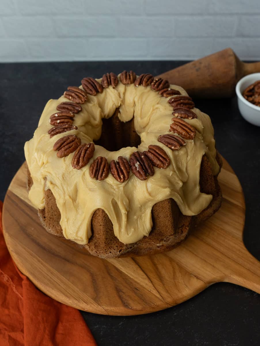 caramel pecan pumpkin bundt cake on a round wood cutting board
