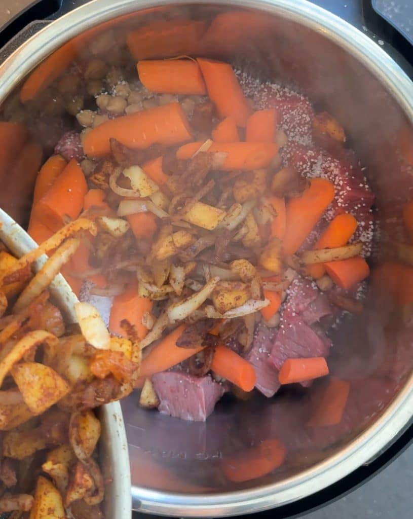 spooning sauteed onions and apples into the slow cooker over top of the stew meat and carrots