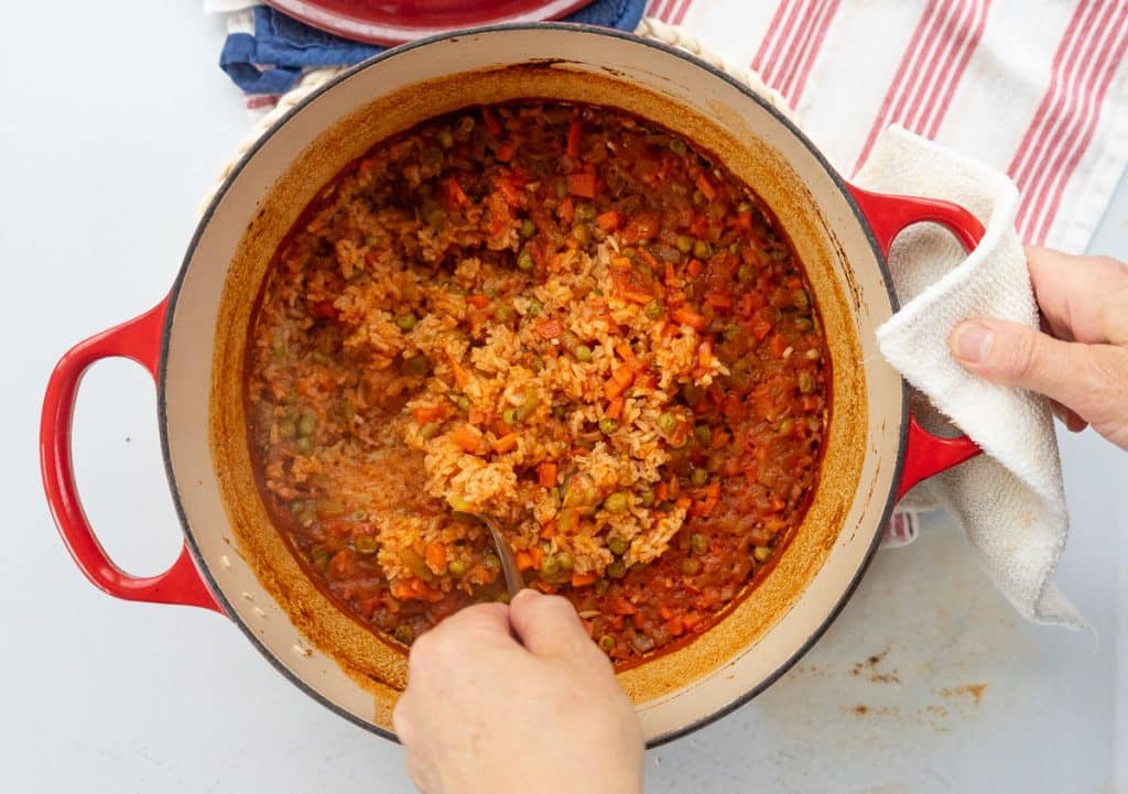 pot of finished spanish rice being fluffed with a fork 