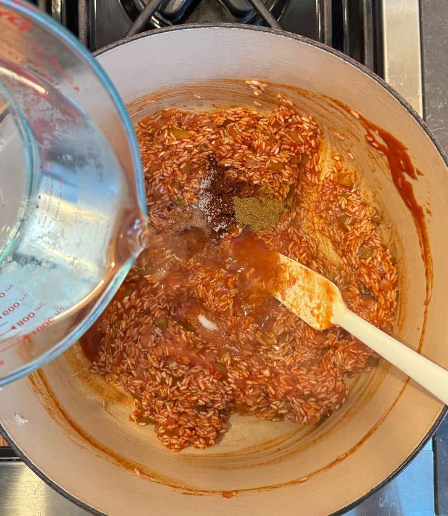 adding water to the spanish rice mixture
