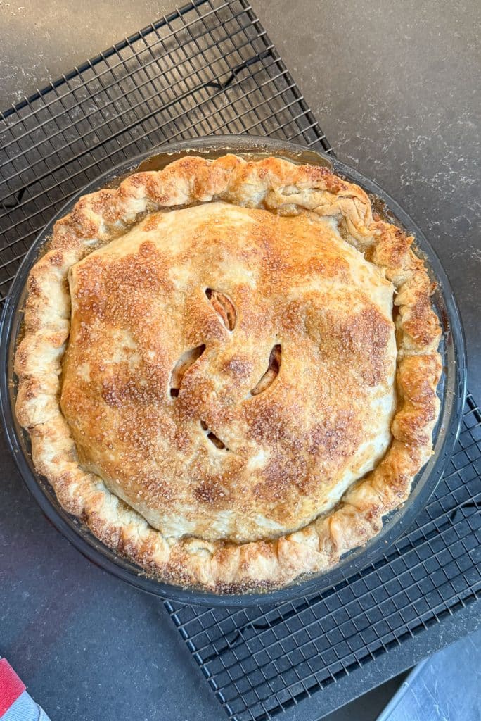 whole baked apple pie on a baking sheet sitting on a black countertop