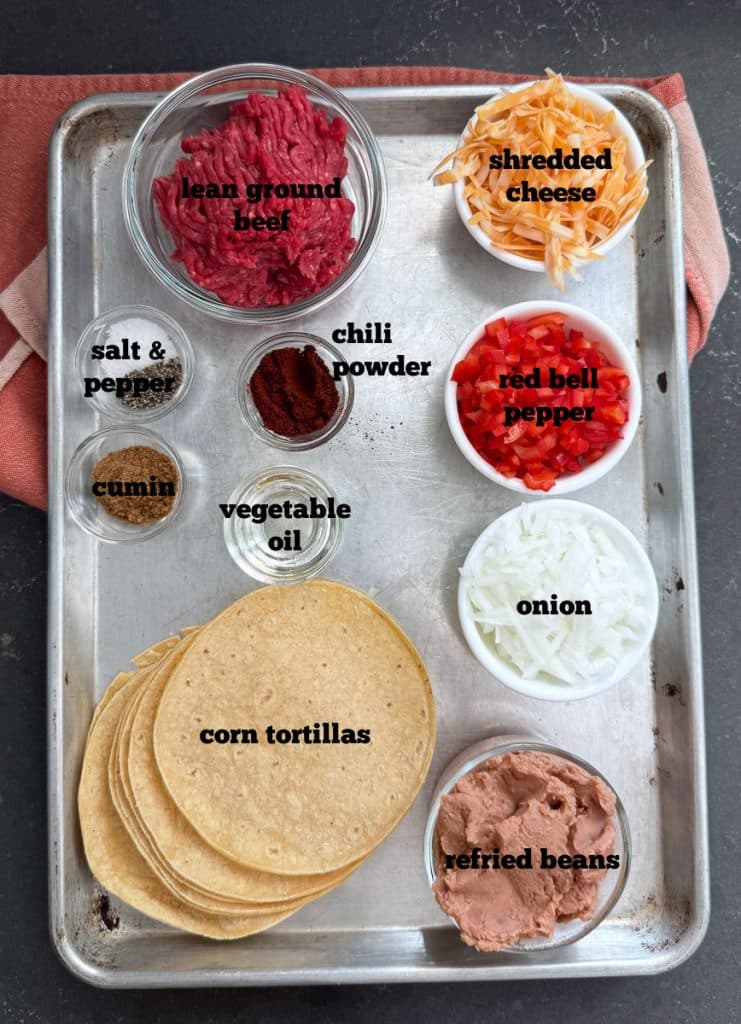 ingredients for beef and bean enchiladas on a baking sheet