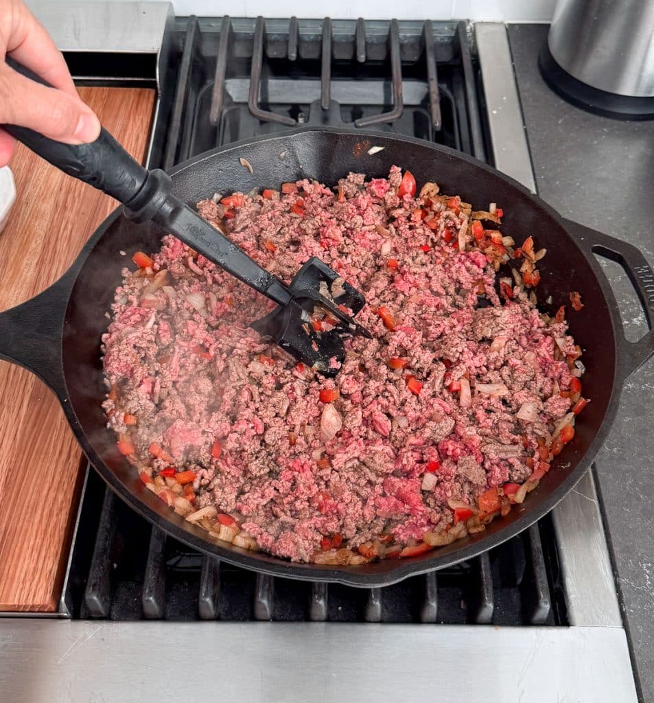 browning the beef in a cast iron skillet on the stove top