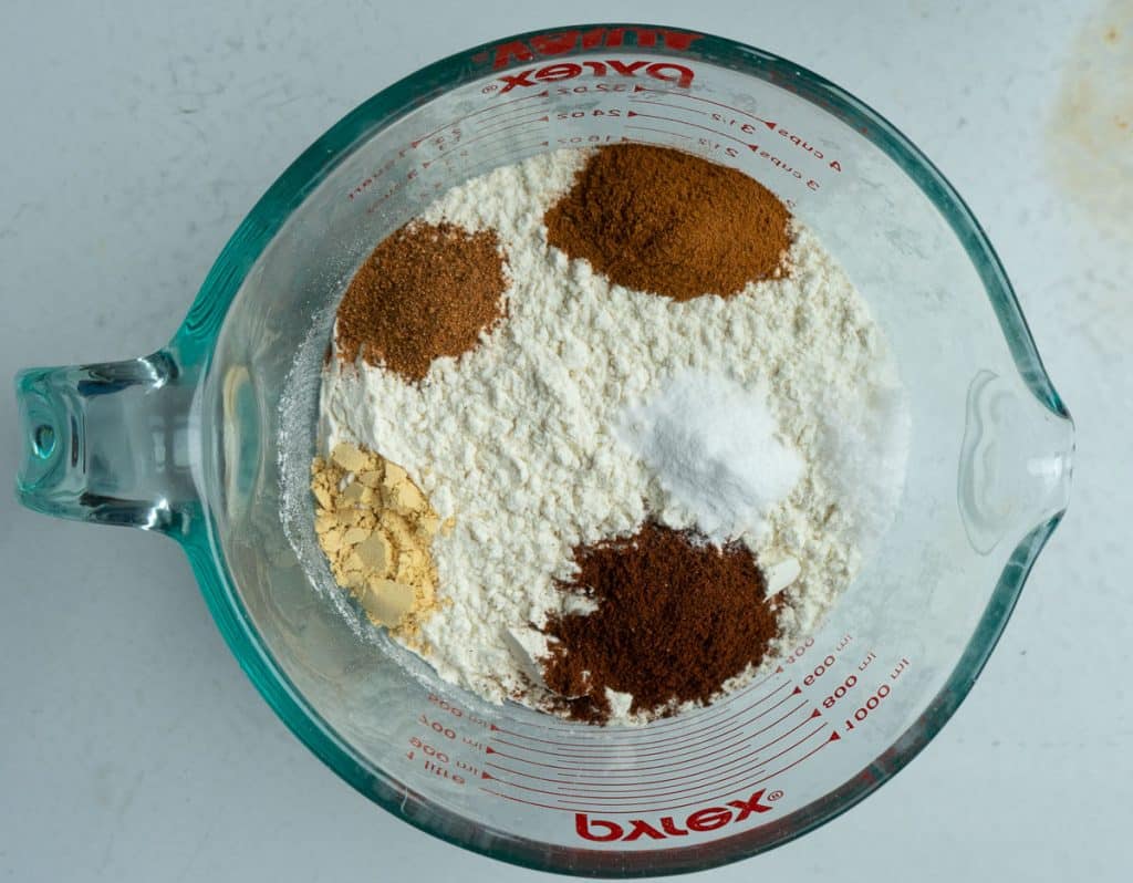 dry ingredients for the brown sugar spice cookies in a clear glass bowl on a white countertop