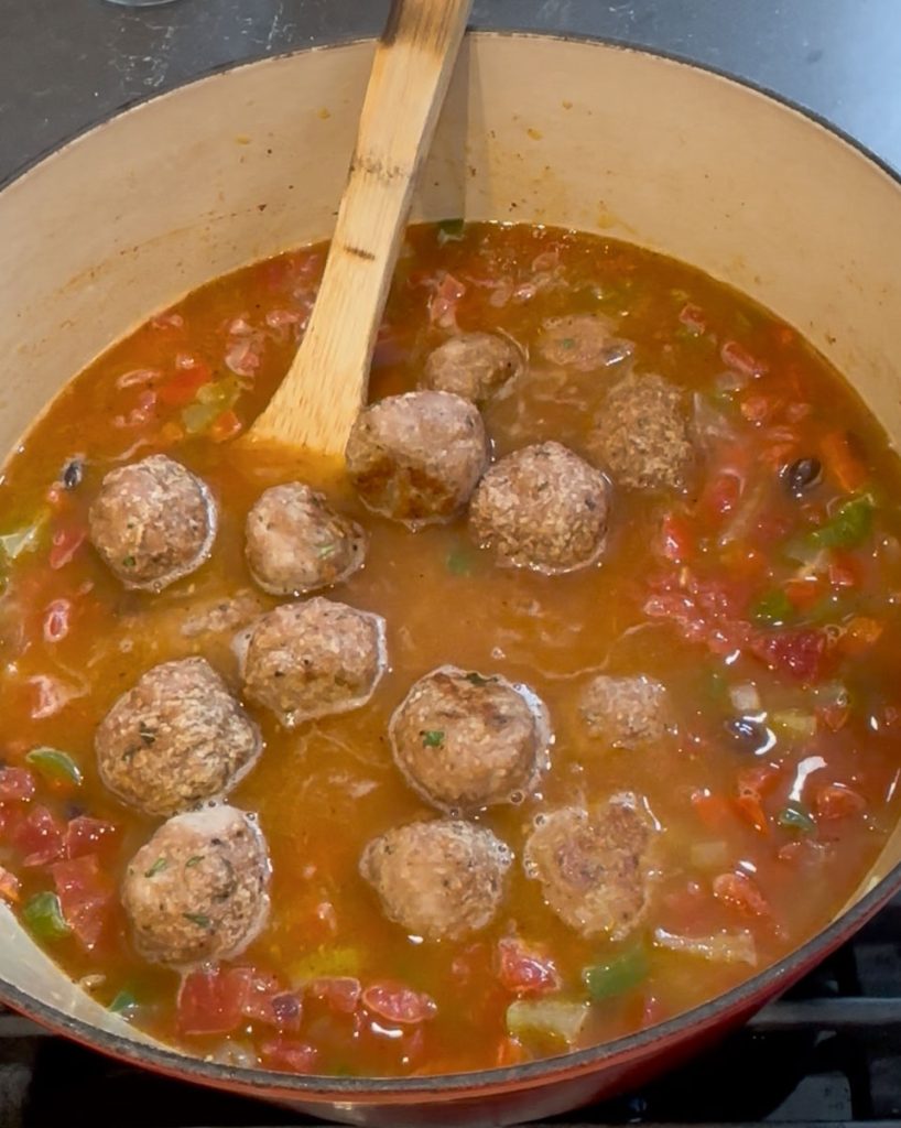 soup simmering on the stovetop with meatballs added to it