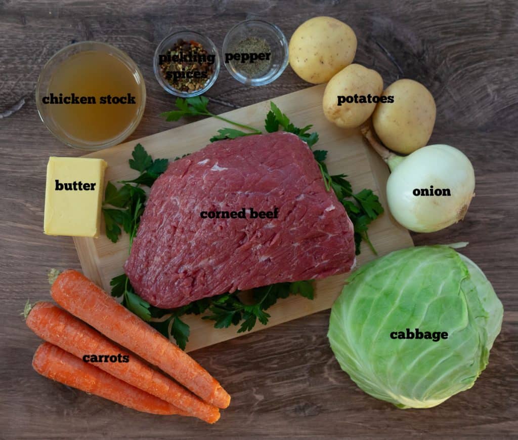 ingredients for boiled dinner on a wood cutting board with a wood back ground