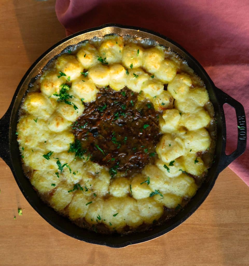 shepherds pie in a cast iron skillet on a wood table top