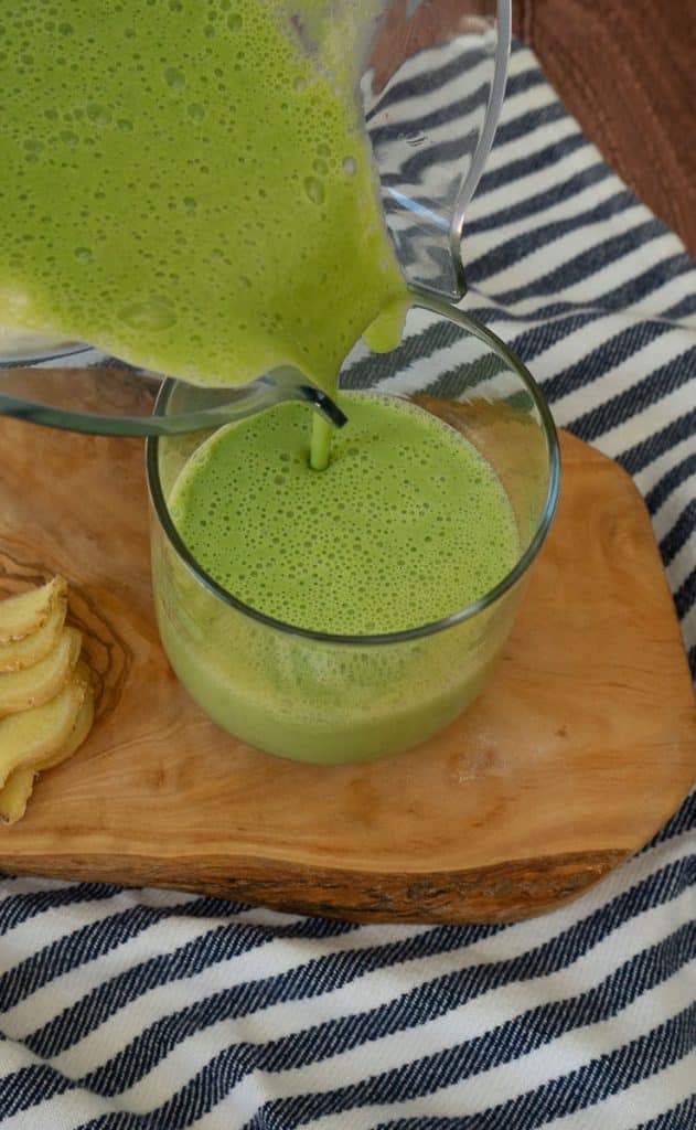 pouring green power smoothie into a glass