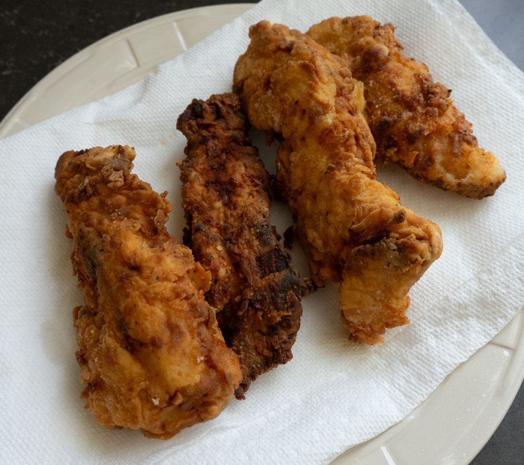 cooked chicken tenders on a plate line with paper towel to soak up the excess oil from frying