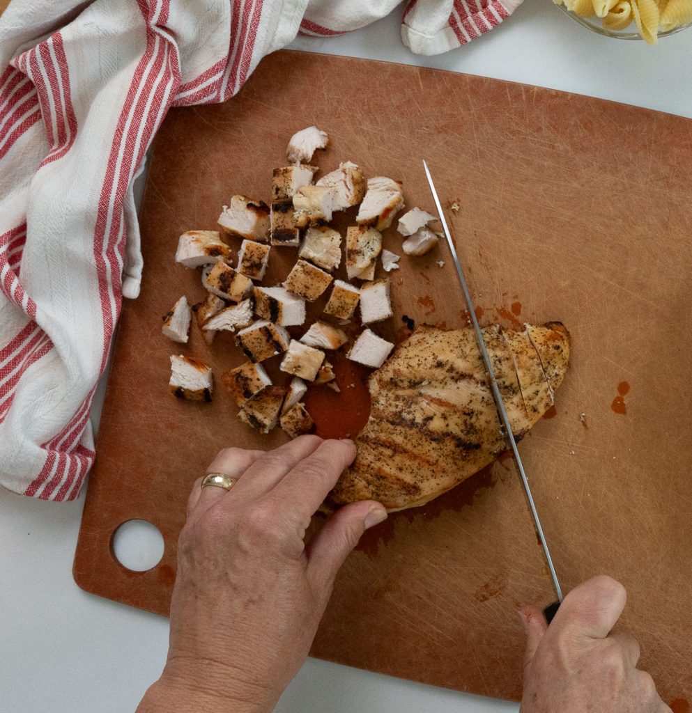 cutting grilled chicken breasts on a wood cutting board 