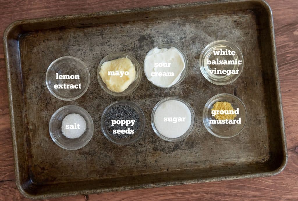 ingredients for lemon poppy seed dressing in small glass dishes on a rustic looking baking sheet