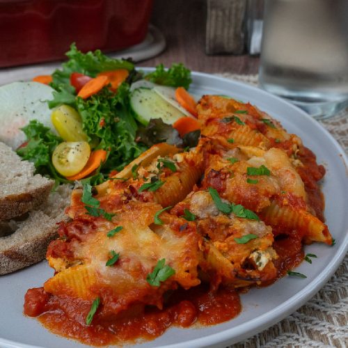 chcheesy chicken and spinach stuffed pasta on a plate with salad