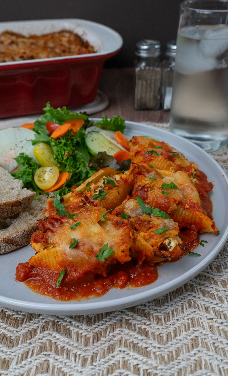 cheesy chicken and spinach stuffed pasta on a plate with salad