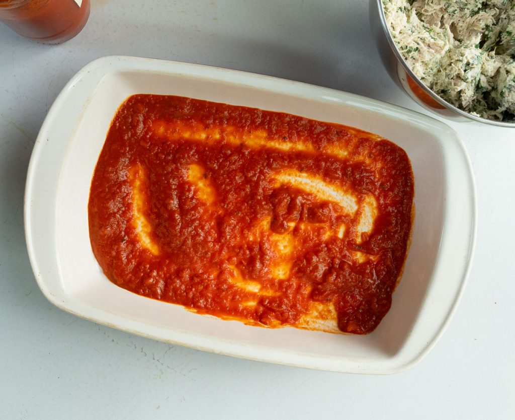 baking dish with marinara sauce in the bottom 