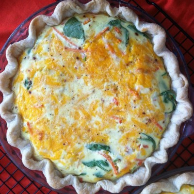 baked quiche in a pie dish with red cloth background