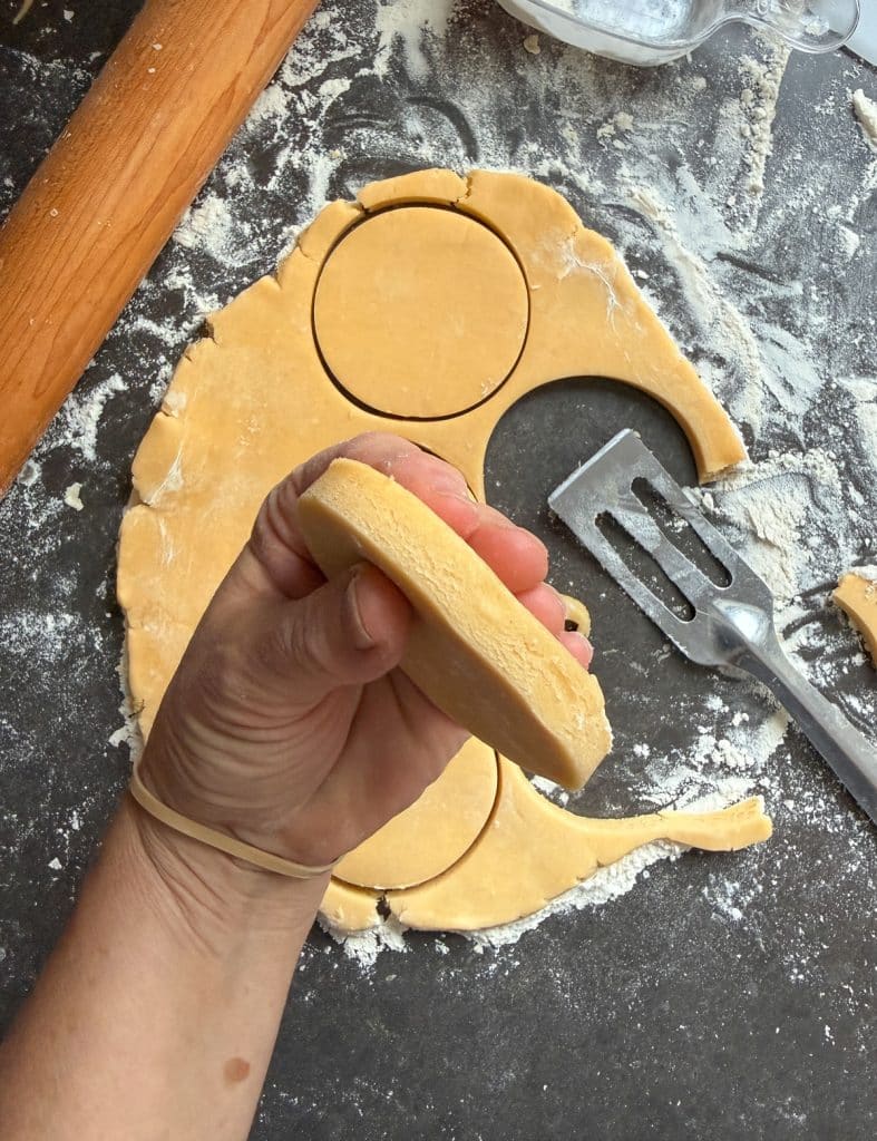 holding a cookie dough that has been cut to show the thickness of the rolled out cookie dough