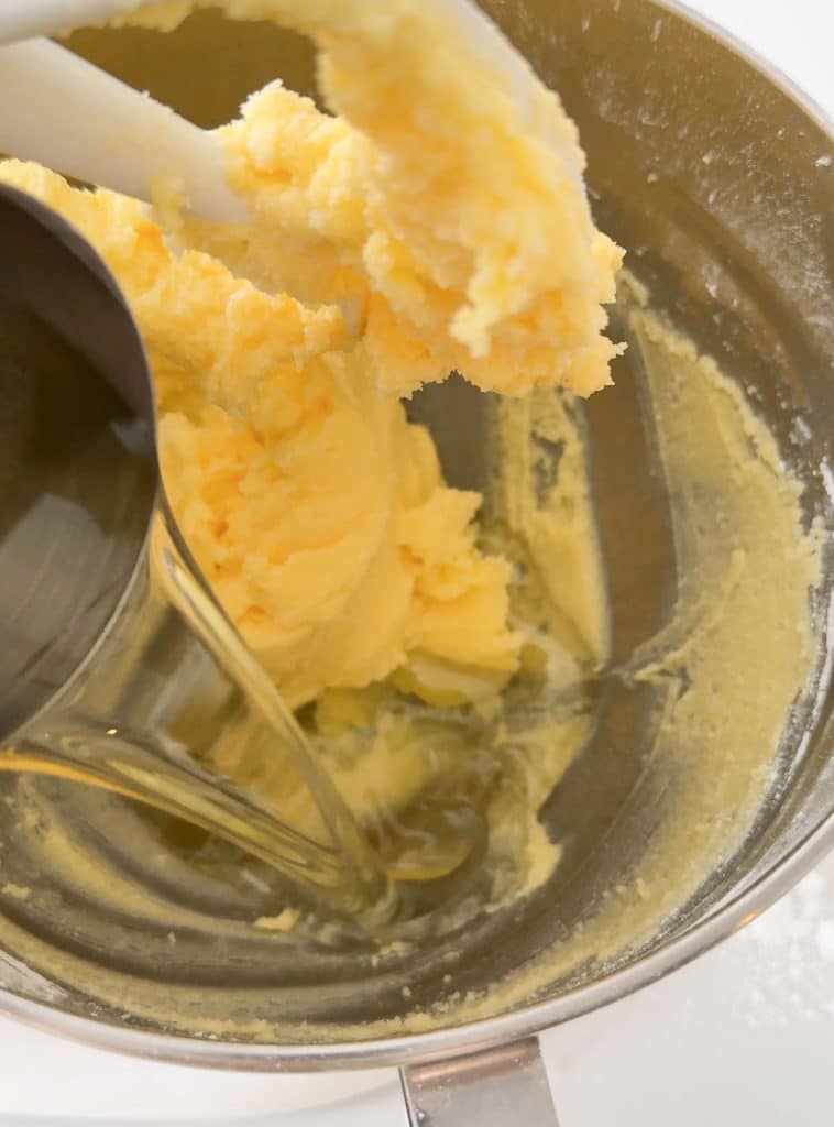 pouring vegetable oil into the butter and sugar mixture in bowl of stand mixer