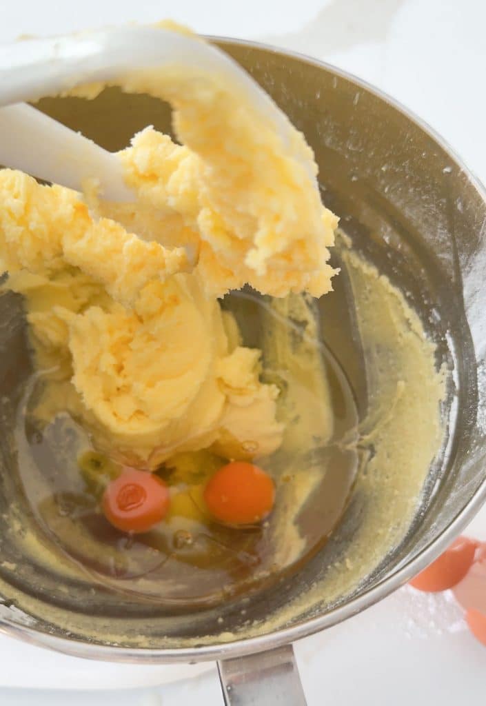 adding eggs and vegetable oil to the sugar butter mixture in the bowl of stand mixer
