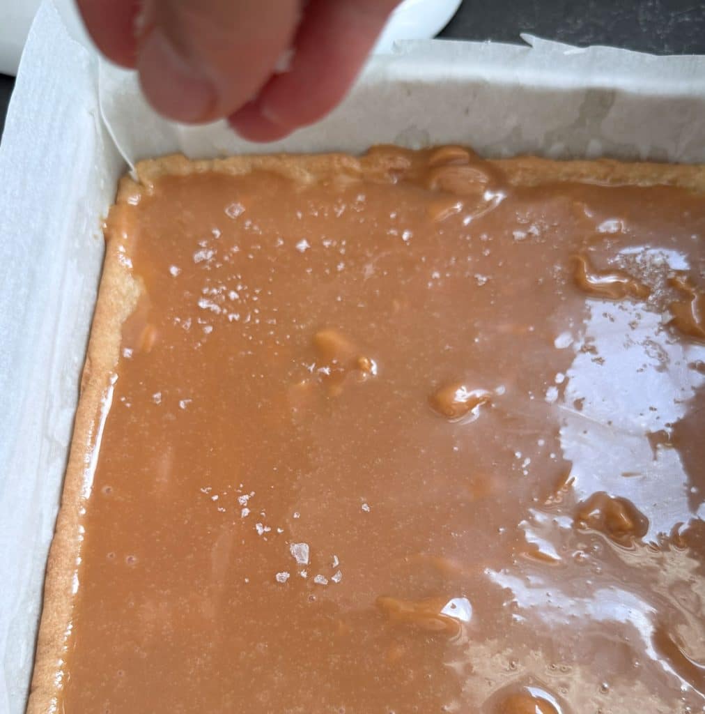 sprinkling flaky salt over caramel layer