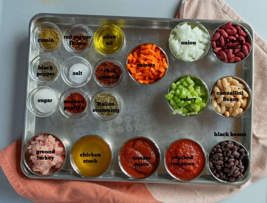 ingredients for three bean turkey soup on a baking sheet that is sitting on a grey countertop