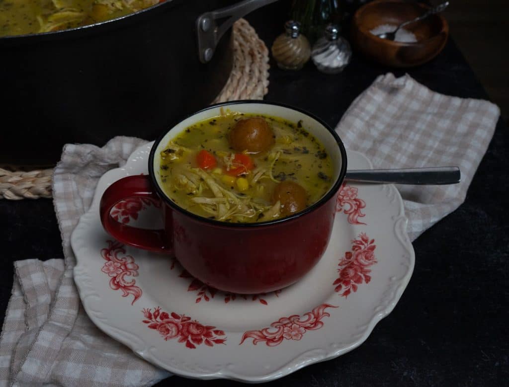 bowl of chicken and red skin potatoe soup with the pot of soup in background to theleft 