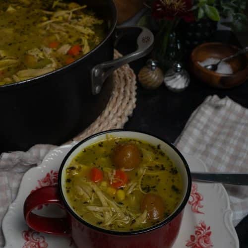 bowl of chicken and red skin potatoe soup with the pot of soup in background to theleft