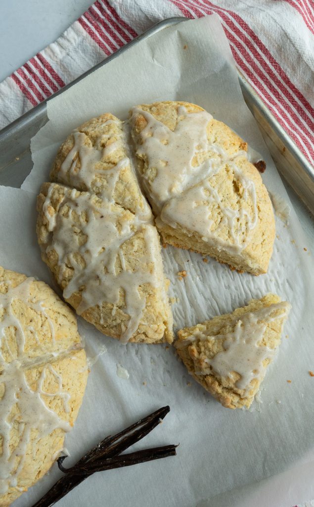vanilla bean cardamom scone with icing on a baking sheet