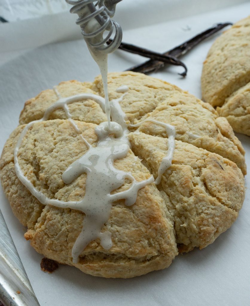 Drizzling icing over warm scones. on a baking sheet. 