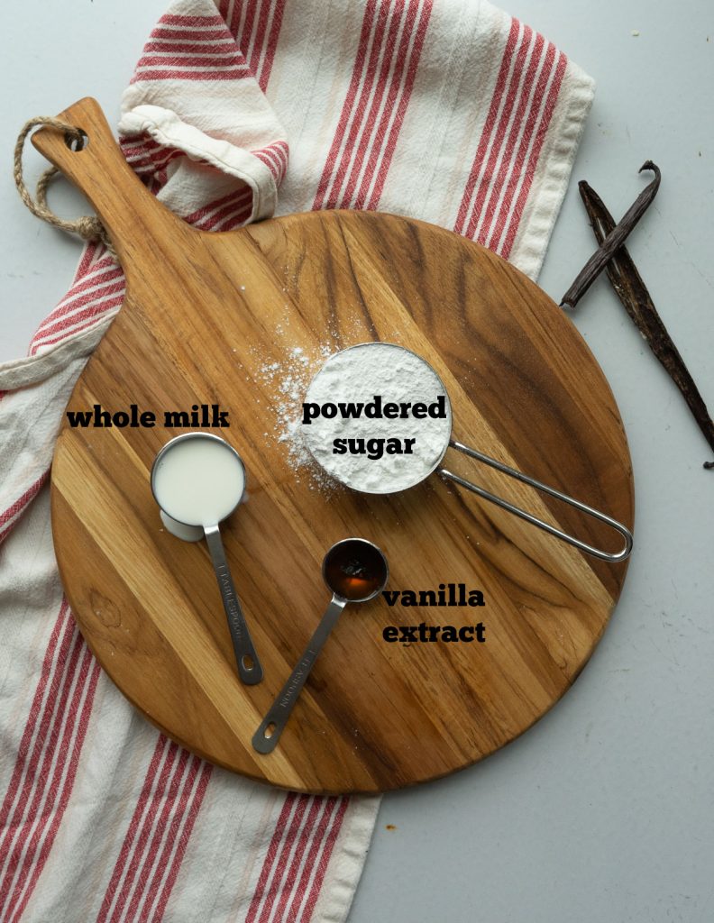 ingredients for vanilla bean glaze on a round wood cutting board