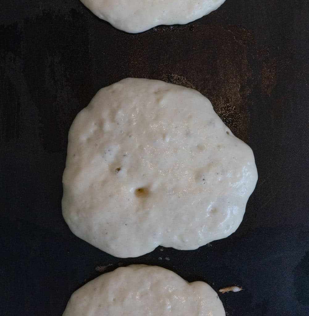 pancakes on the griddle showing when the correct time is to flip when there are bubbles and the edges appear dry