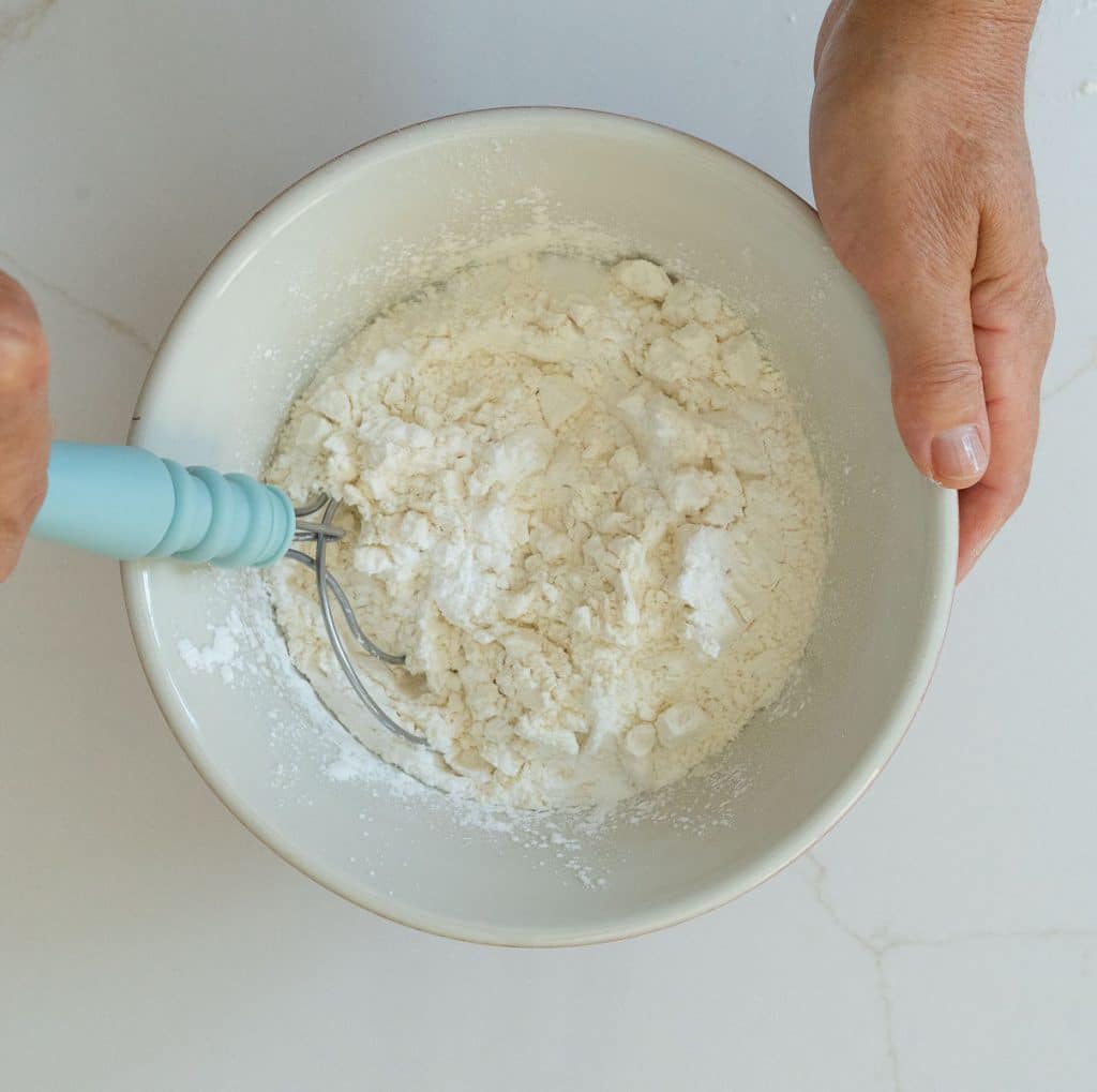 Dry ingredients being mixed in a bowl on a white counter top