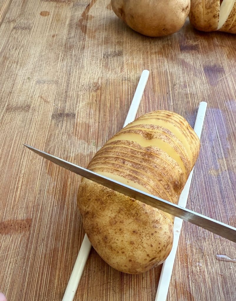 demonstrating cutting thin slices almost all the way through a potato