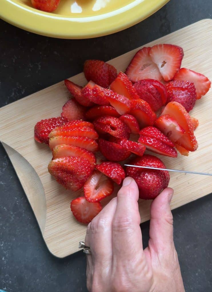 slicing strawberries on a wood cutting board