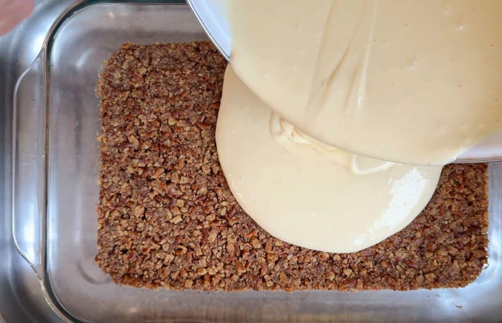 pouring cheesecake layer over pretzel crust