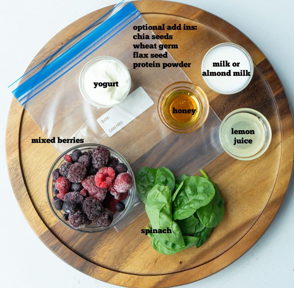 ingredients for freezer smoothie on a round wooden cutting board on a white countertop