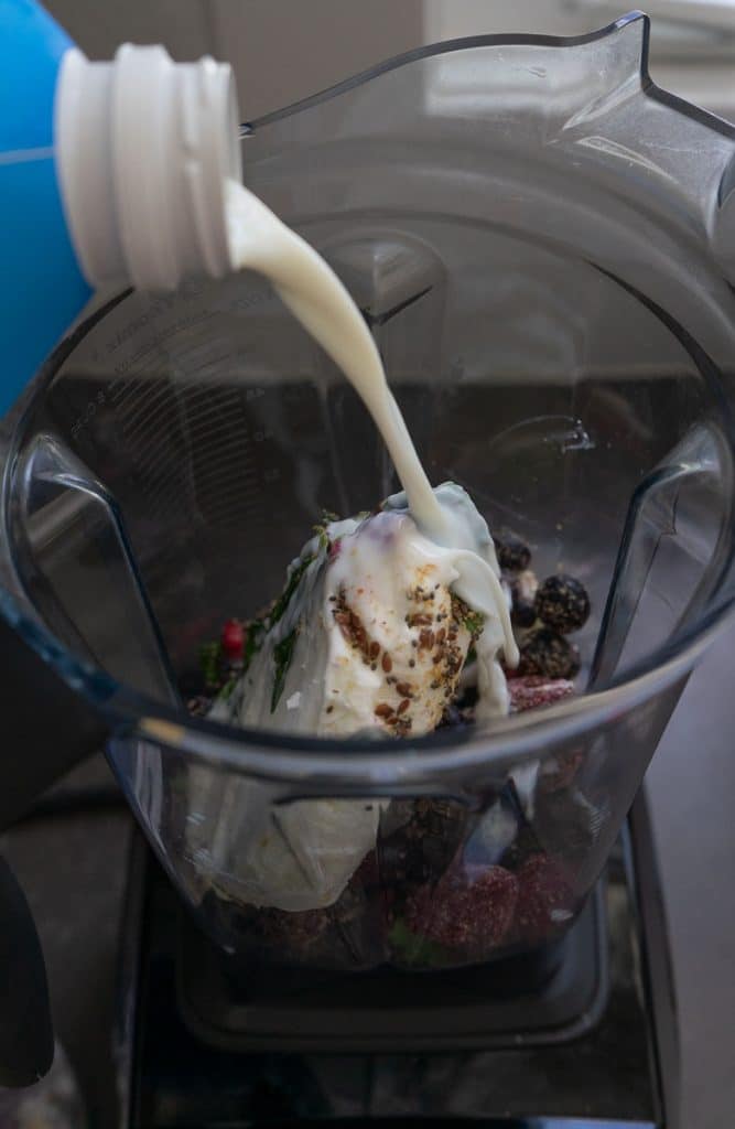 pouring milk into blender with the other smoothie ingredients