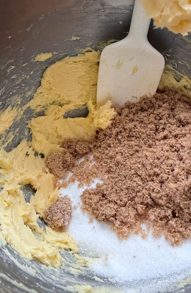 butter and sugar in a mixing bowl with a white spatula in the bowl 