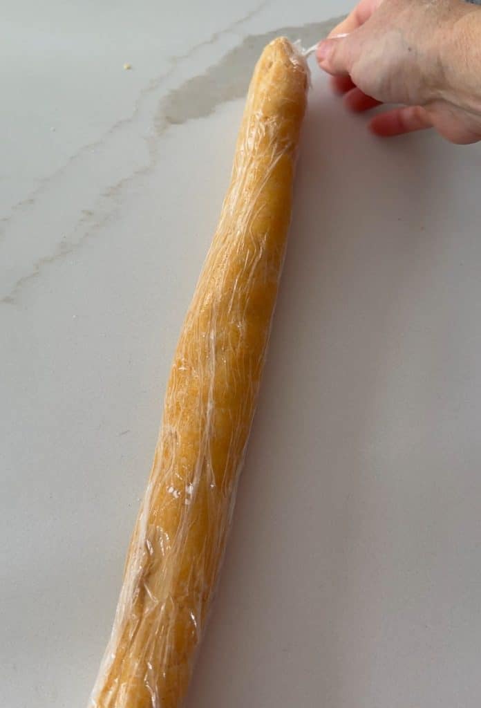 tube of cheese cracker dough in plastic wrap on a white countertop