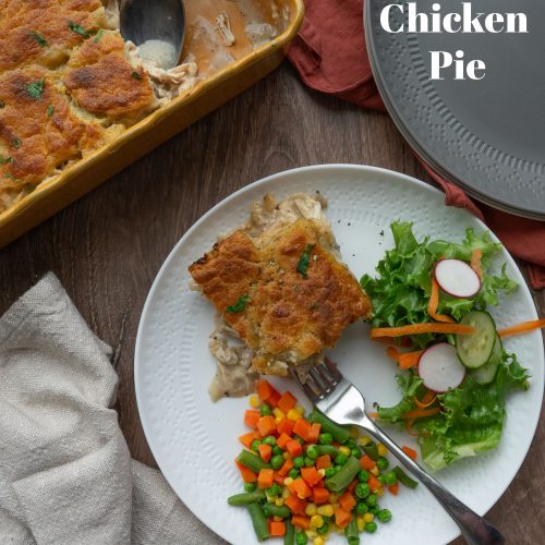 chicken pie on a white plate with mixed veggies and a salad casserole dish is to the top of the plate of food