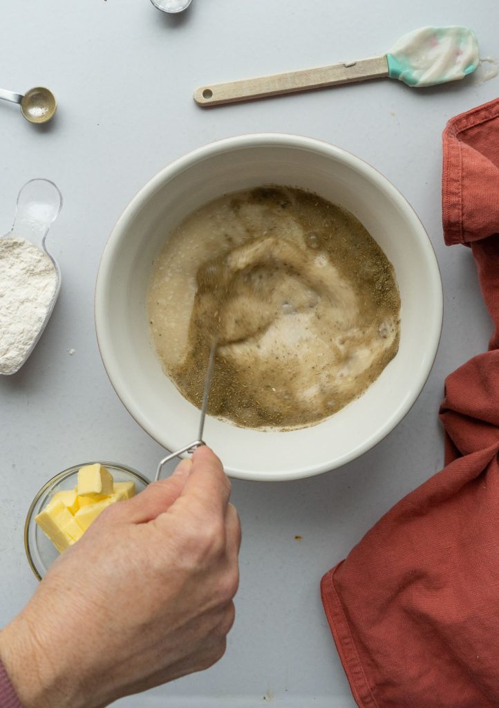 mixing cream sauce in a bowl with a whisk on a gray countertop