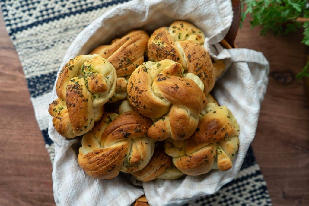 op view of a basket of garlic knots on a wood countertop on a blue and tan striped placemat