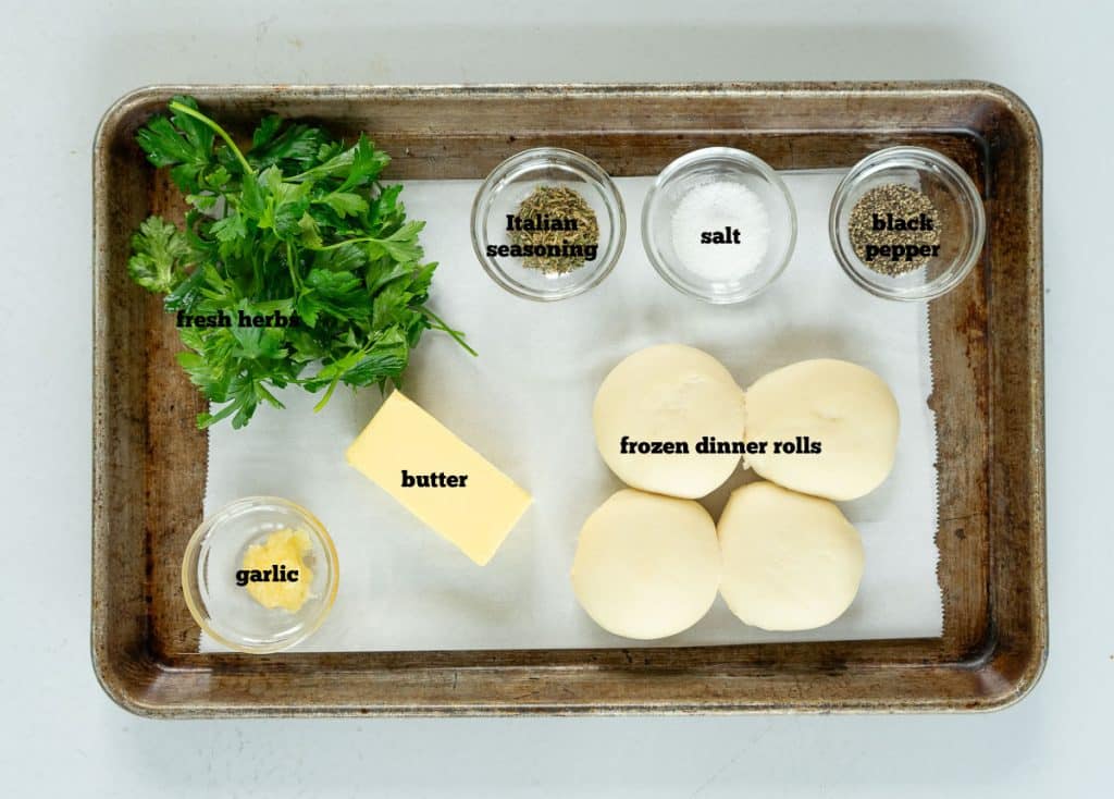 ingredients for garlic knots on a baking sheet with parchment paper on it sitting on a white countertop